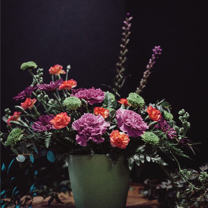 Mixed pink and orange flowers in a green stoneware pot